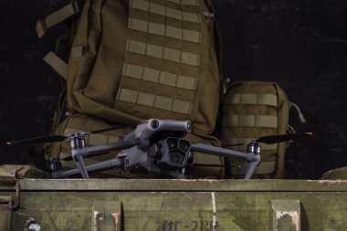 Kameralı İHA. Üç lensli drone. Askeri bir sırt çantasının arka planına karşılık Quadcopter. Aşağıdan drone görünümü.