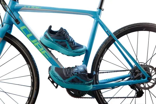UKRAINE, KYIV - 27 Temmuz 2024: Küp yol bisikleti ve Salomon spor ayakkabıları. Turkuaz spor ayakkabılar ve beyaz arka planda bisiklet. İzole edilmiş. Ön görünüm.