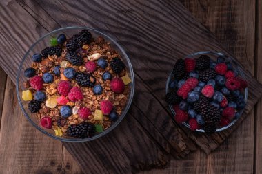 Yaz ormanı böğürtlenlerinin karışımı. Böğürtlen ve granola karışımı. Böğürtlenli cam kaseler. Eski tahta arkaplan.