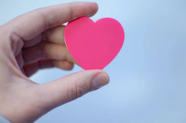 Pink heart in a woman\'s hand on a blue background