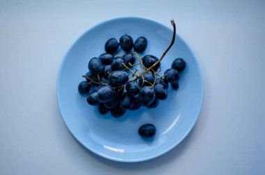 Mavi bir tabakta bir demet olgun mavi üzüm