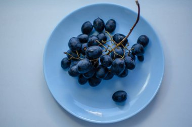 Mavi bir tabakta bir demet olgun mavi üzüm