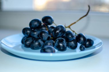 Mavi bir tabakta bir demet olgun mavi üzüm