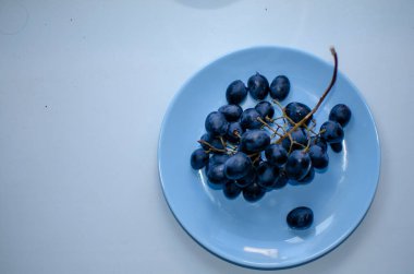 Mavi bir tabakta bir demet olgun mavi üzüm