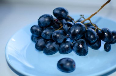 Mavi bir tabakta bir demet olgun mavi üzüm