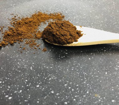 Toz yığını manzarası, siyah seramik arka planda izole edilmiş tahta kaşıkta hazır kahve.