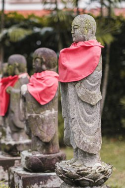 Singapore - July 9 2023: Row of Mini Stone Monk Statues with Red Scarfs