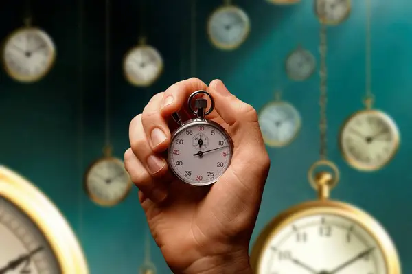 A hand clutching a stopwatch as time passes through flying clocks. concept of time that flies
