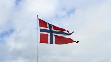 Güzel Norveç bayrağı rüzgarda sallanıyor. Arka planda yumuşak bir gökyüzü var.