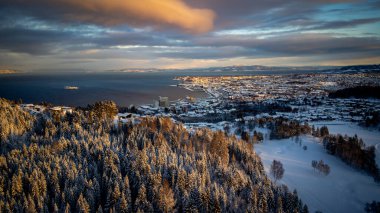 Trondheim, Norway. Aerial view of the city center in winter in Trondheim, Norway with snow, river and historical colorful buildings clipart