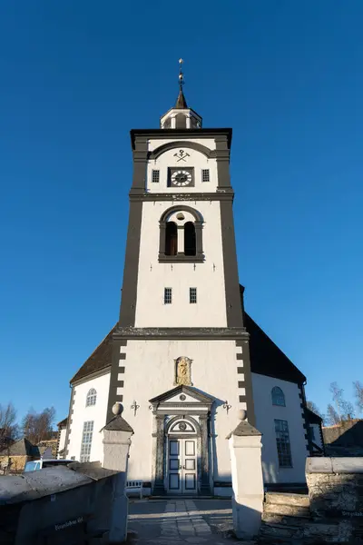 stock image The Roros Church stands amidst of traditional Scandinavian wooden homes, under a cloudy sky in this heritage-rich Nordic village