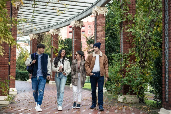 group of four multicultural college friends walking back from university