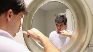 Dişlerini fırçalayan genç adamın 4K video görüntüsü aynaya yansıdı.