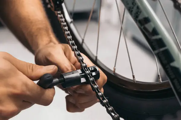 closeup mechanic hands changing bike chain with tool in the workshop