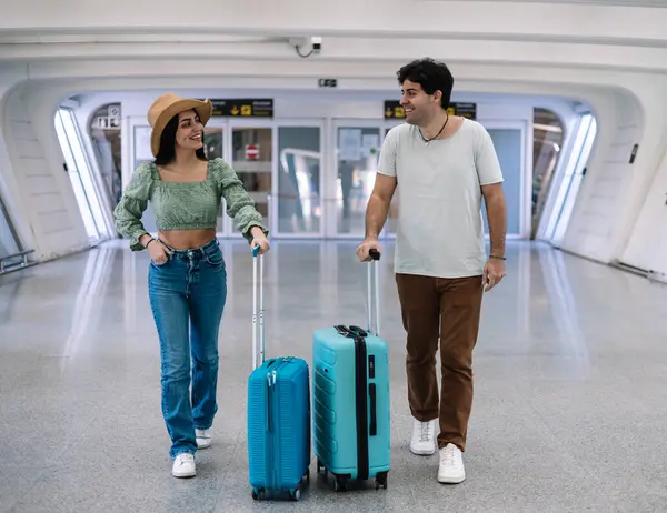 multicultural couple with their luggage at the airport to board on their honeymoon