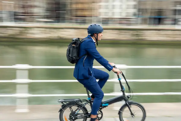 A dynamic shot capturing the movement of a businessman commuting through the city on his electric bike, promoting sustainable transportation