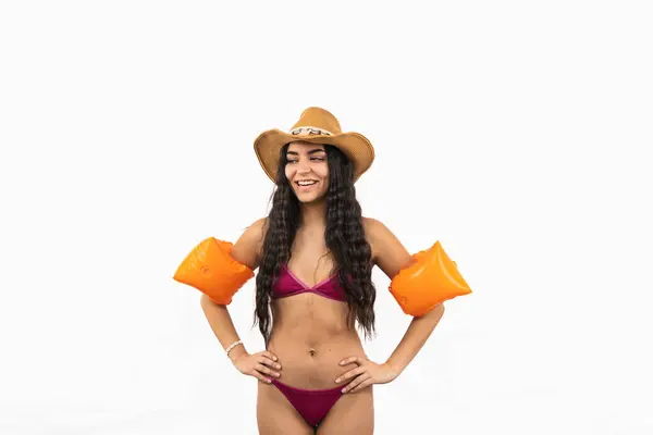 Bikini ve turuncu kollu genç Latin kadın beyaz arka planda güzel bir plaj gününde poz veriyor.