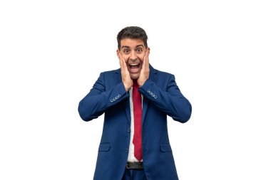 Ellerini yüzüne dayayıp sevinç ve şaşkınlığını ifade eden bir iş adamı. Şık bir mavi takım elbise ve kravat giymişti. Yüzündeki ifade mutluluk ve heyecan saçıyordu. Beyaz arka plan.
