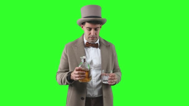 20世纪初的一位古董先生 戴着一顶圆顶礼帽和一件风衣 品尝着一瓶陈酿的白葡萄酒背景中的一小口 — 图库视频影像