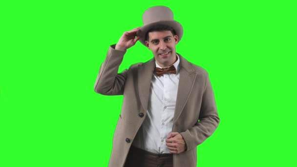 20世纪初的一位绅士 头戴圆顶礼帽 身穿战壕外套 彬彬有礼地向摄像机致意 手里拿着一顶彩色绿色的帽子 神气十足 — 图库视频影像