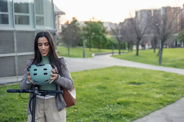 Kopya uzay iş kadını kaskını kafasına yerleştirirken görüldü, işe giderken elektrikli scooterını kullanmaya hazırlanıyordu. Bu resim işe gidip gelmeye modern yaklaşımı yakalar.