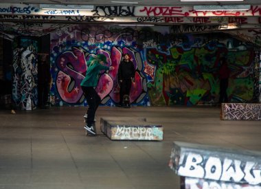 04 / 01 / 2023, Londra, patenciler, Londra 'da renkli graffitilerle süslenmiş canlı bir kaykay parkında kaykay yapmaktan hoşlanıyorlar. Görüntü kaykayın enerjik atmosferini ve şehir kültürünü yakalıyor.