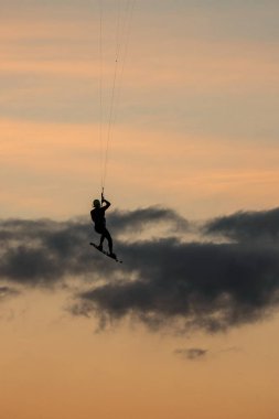 10 / 27 / 2023, Tarifa, İspanya, Tarifa 'da, Tarifa' da gün batımına karşı atlayan bir uçurtmanın silueti, rüzgar ve uçurtmasıyla savruluyor..