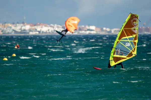 stock image 10/27/2023, Tarifa, Spain, man windsurfs in the waters of the Strait of Gibraltar in Tarifa, while in the background, another man jumps with his wing foil, harnessing the wind for a thrilling session