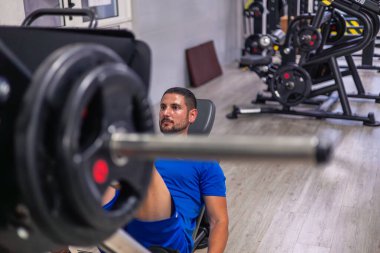 Genç fitness sporcusu spor salonunda bacak presi makinesiyle bacak kasları üzerinde çalışıyor. Bu görüntü, düşük vücut gücü eğitiminin yoğunluğunu ve odak noktasını yakalar.