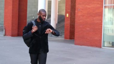 Afrikalı işadamı, iş toplantısına geç kaldığı için İspanyol meslektaşını ofis dışında azarlarken görülüyor. Profesyonel gerginliği yakalıyor ve dakikliğin önemini vurguluyor.