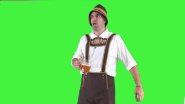Geleneksel Oktoberfest kıyafeti giymiş genç Bavyeralı bir adam elinde bira bardağı tutarken sıkılmış görünüyor. Oktoberfest festivalinin hareketli atmosferine rağmen, ilgisiz bir kroma anahtarı gibi görünüyor.