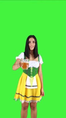 Geleneksel Oktoberfest kıyafeti giymiş dikey Bavyeralı kız kameraya doğru bira bardağıyla kadeh kaldırıyor. Neşeli ifadesi canlı ve neşeli atmosfer krom anahtarını yakalıyor.