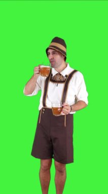 Geleneksel Oktoberfest kıyafeti giymiş dikey genç Bavyeralı adam iki bira bardağından içiyor. Festivalden keyif alışını yakalıyor, canlı ve kutlama atmosferini yansıtıyor.