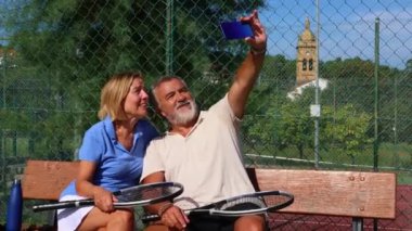 Yaşlı bir çift tenis maçından sonra bir bankta oturur ve akıllı telefonlarıyla selfie çekerken gülümserler. İkisi de raketlerini tutuyor ve spor kıyafetlerini giyiyor. Rahatlamanın tadını çıkarıyorlar.