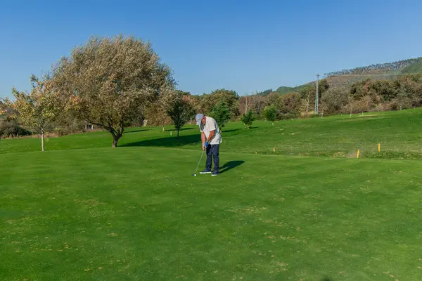 Copyspace yaşlı golfçüsü, golf sopasıyla topa vurmaya hazırlanırken derinden konsantre oluyor. Görüntü, başarılı bir vuruş için gereken sakinliği ve odaklanmayı yakalar