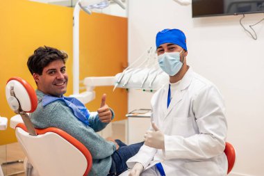 Modern bir diş kliniğinde başarılı bir diş muayenesinden sonra mutlu dişçi ve hasta memnuniyet belirtileri gösteriyor. Oral hijyen ve profesyonel diş bakımının önemini vurgulamak