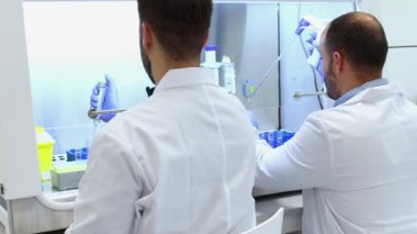 Beyaz laboratuvar önlükleri giyen bilim adamları steril laboratuvar içinde titiz bir araştırma yapıyorlar. Gelişmiş bilimsel ekipman ve hassasiyet teknikleri kullanarak örnekleri analiz ediyorlar.