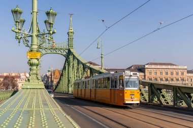 02 / 17 / 2024, Budapeşte. Budapeşte, Macaristan 'daki Liberty Köprüsü' nü geçen sarı tramvay, Buda ve Pest 'i Tuna Nehri üzerinden birbirine bağlayan önemli bir ulaşım merkezi ve turizm merkezi.