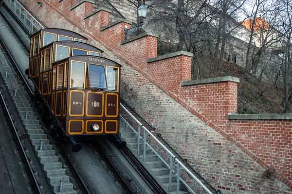02 / 17 / 2024, Budapeşte. Kahverengi ve sarı Budapeşte Kalesi Funicular, Buda Kalesi 'nin bulunduğu Castle Hill' in tepesine doğru raylara tırmanıyor.