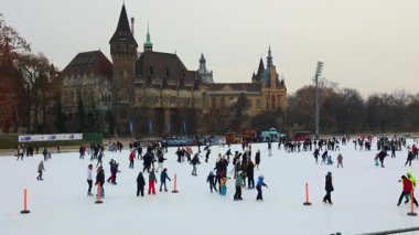 02-17-2025, Budapeşte. Turistler ve yerliler Budapeşte Şehir Parkı 'ndaki bir buz pateninin keyfini çıkarırken, manzaralı Vajdahunyad Şatosu manzaralı bir kış manzarası yaratıyor.