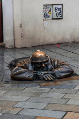 02-20-2025, Bratislava. Rögar kapağından çıkan bir işçinin bronz heykeli olan Cumil, Bratislava, Slovakya sokaklarına bir neşe katıyor.
