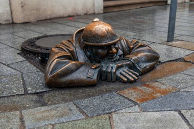 02-20-2025, Bratislava. İş yerinde rögar kapağından bakan bir adamın ikonik bronz heykeli olan Cumil, Bratislava, Slovakya 'da popüler bir turistik ilgi odağı ve kentin sokaklarına biraz mizah katıyor.