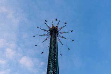 02-22-2025, Viyana, Praterturm, yüksek zincirli bir atlıkarınca salıncak, turistleri Viyana 'nın Prater eğlence parkının tepesine çıkartıyor, mavi bir yaz gökyüzü altında gökyüzünün panoramik manzarasını sunuyor.