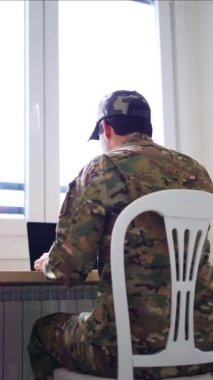 kamuflaj üniformalı bir asker tele-çalışma seansını bitiriyor, bilgisayarını kapatıyor, sandalyesinden kalkıyor ve ofisini terk ediyor.