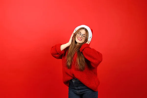 Christmas playlist, a girl in headphones and a red sweater dances to the music. New Year celebration.