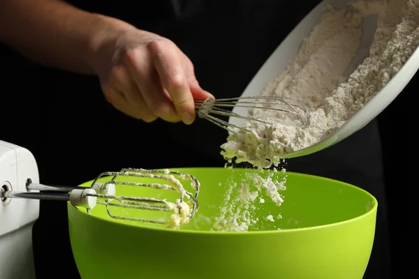 Cooking biscuit dough, the hands of the cook pour flour into the bowl.