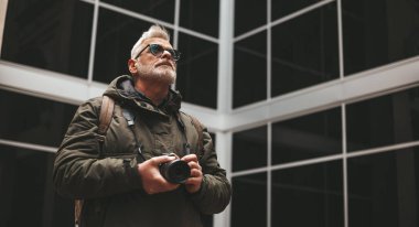 Elinde kamera olan olgun bir gazeteci. Serbest muhabir, gezgin..