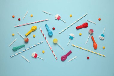 Bir parti için neşeli bir dekor, mavi arka plan. Tatlı şekerler, parlak toplar, şenlikli mumlar ve pipetler..