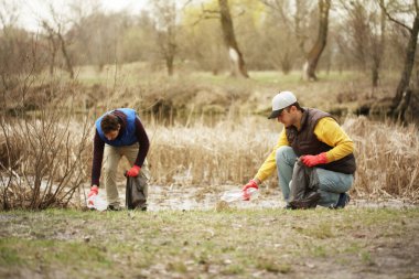 Bağış gönüllüleri ormandaki çöpleri topluyor, doğayla ilgileniyor. Parkta bahar temizliği, çöpler ve çöpler..