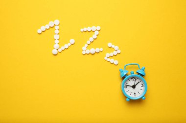 Uyku hapları ve çalar saat, uykusuzluk konsepti. Gece depresyonu, endişe.